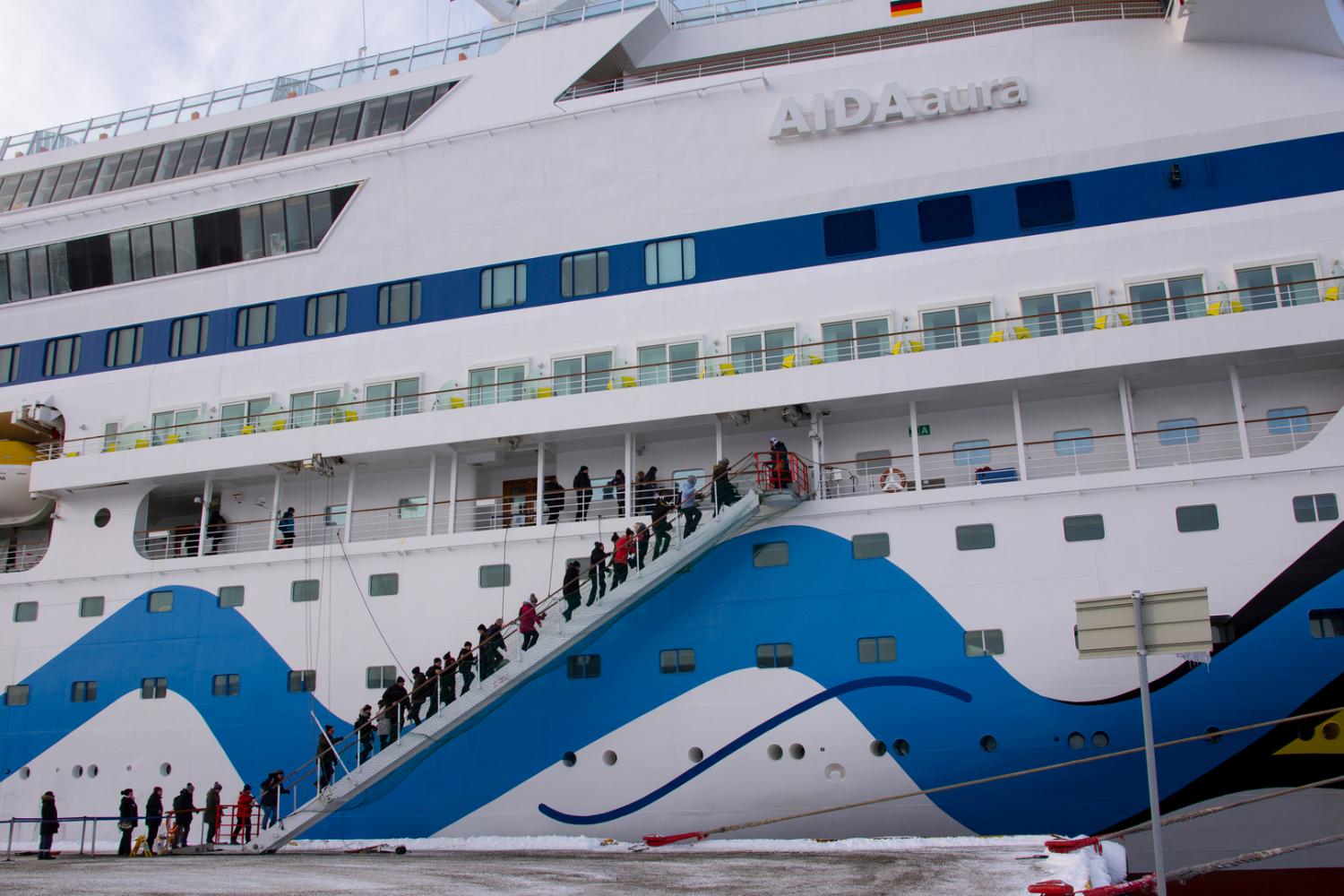 stort cruiseskip med mennesker som g&aring;r ombord