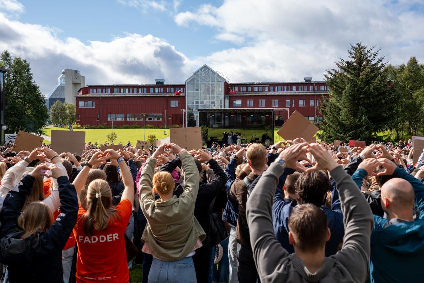 Masse studenter viser hjertetegn til universitetsledelse p&aring; scene ute. 