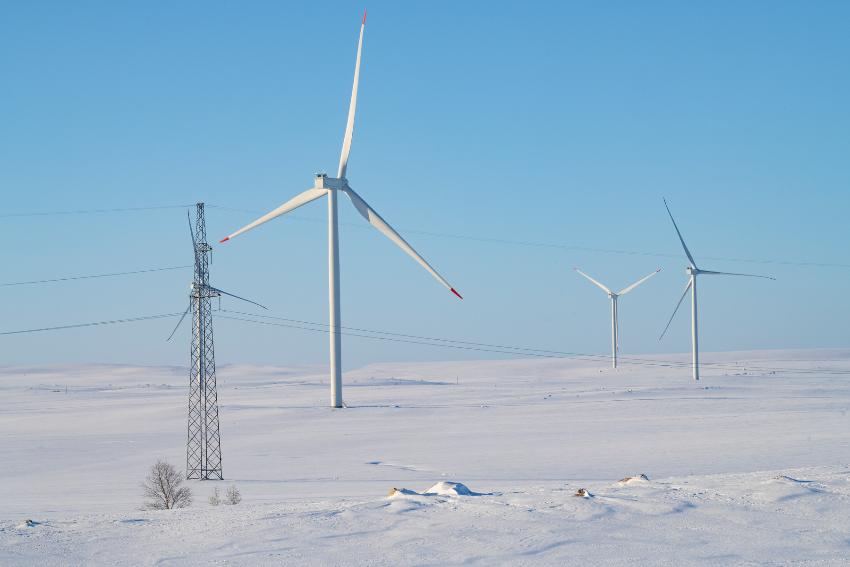 Vindmøller og energimaster i snødekt landskap.