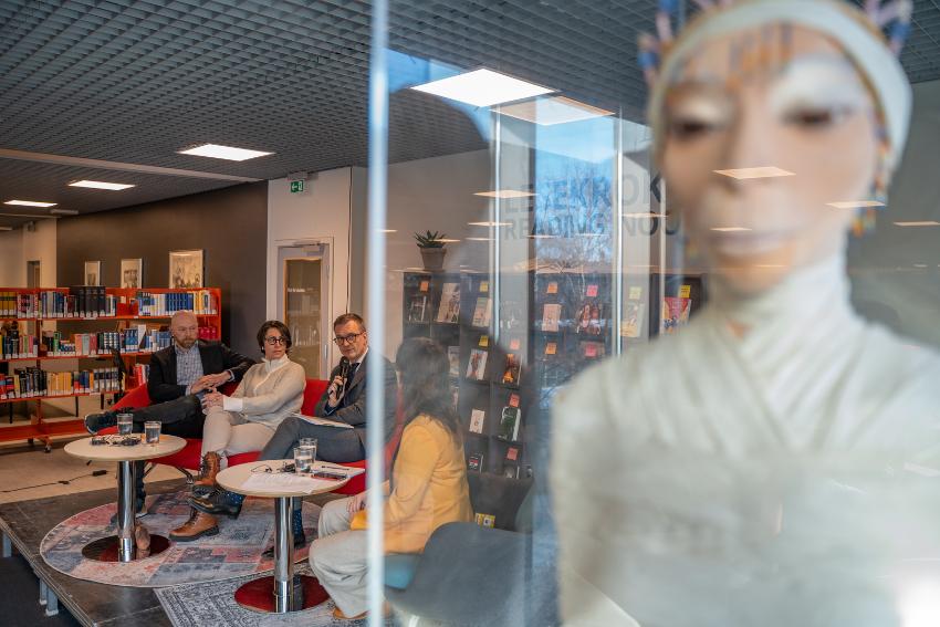 To menn og to kvinner debatterer i et universitetsbibliotek. 