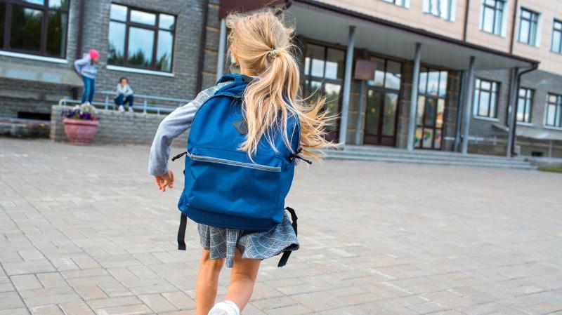 dame med kort h&aring;r og briller som st&aring;r ute foran universitetsbygg