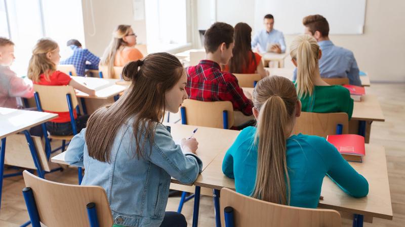 skoleelever som sitter ved skolebenken en elev lener seg mot den andre