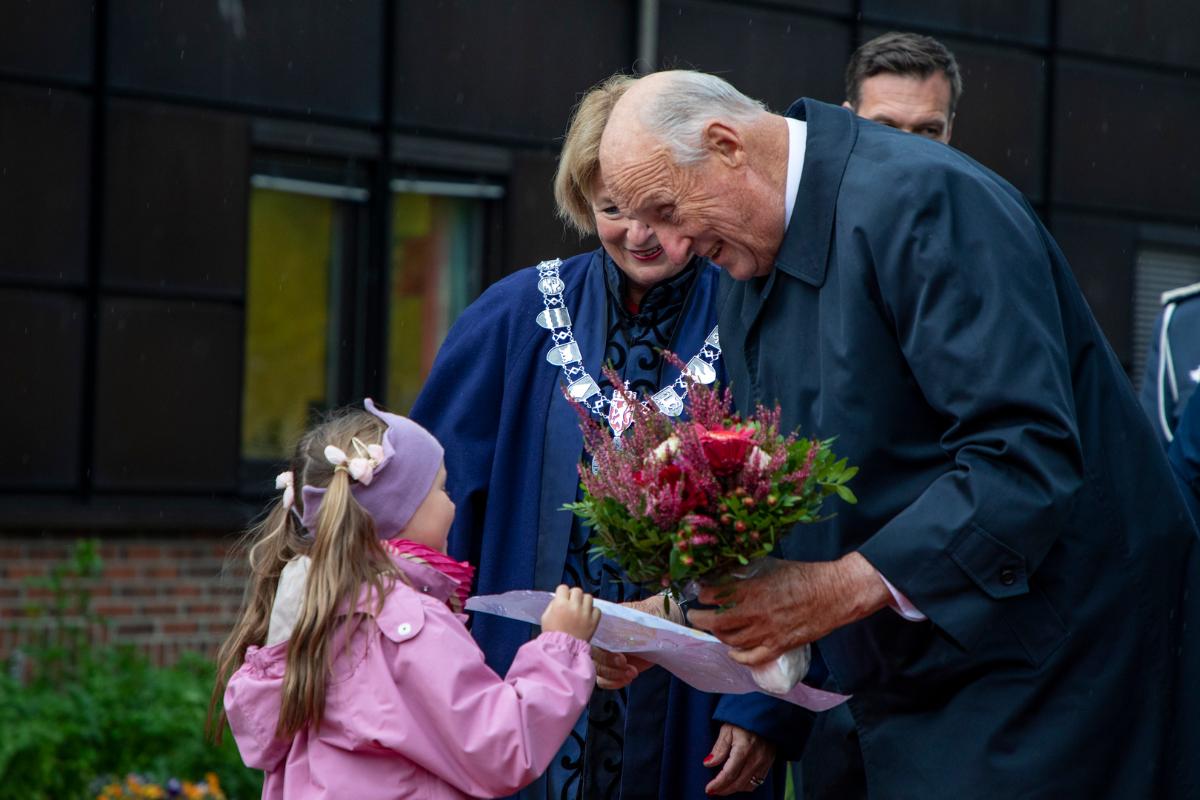 En eldre mann f&aring;r blomster og hilser p&aring; en jente.