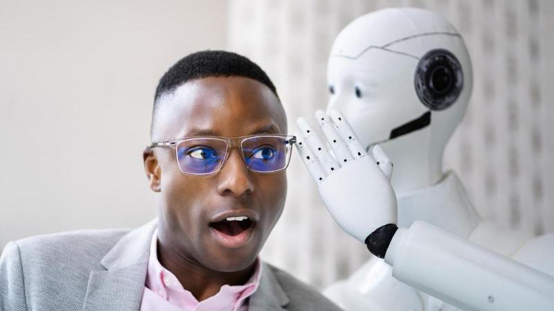 robot som visker noe i &oslash;ret til en mann med m&oslash;rk hudfarge og briller