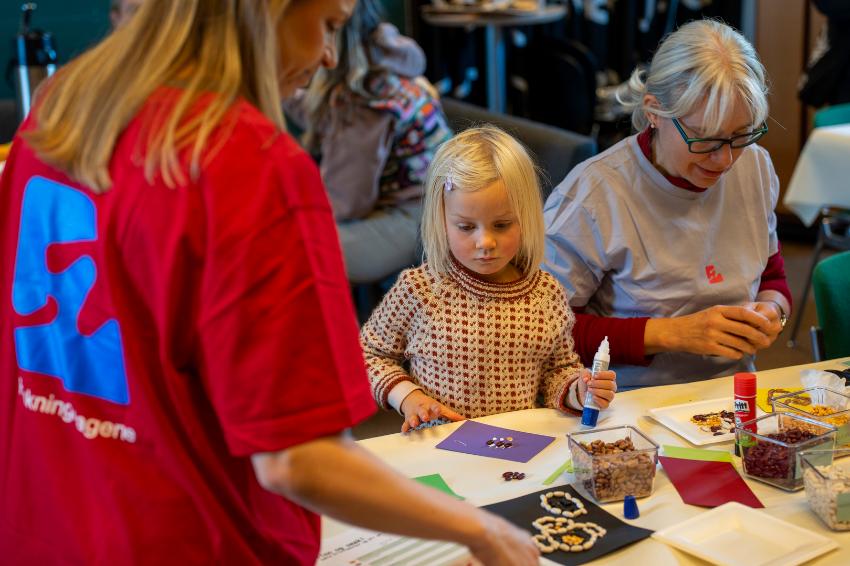liten jente som lager noe kunst og håndverk sammen med forskere