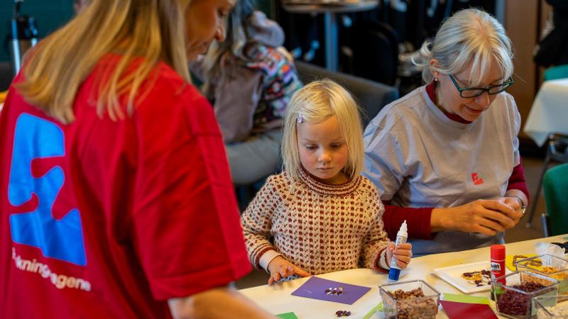 liten jente som lager noe kunst og h&aring;ndverk greier sammen med to forskere