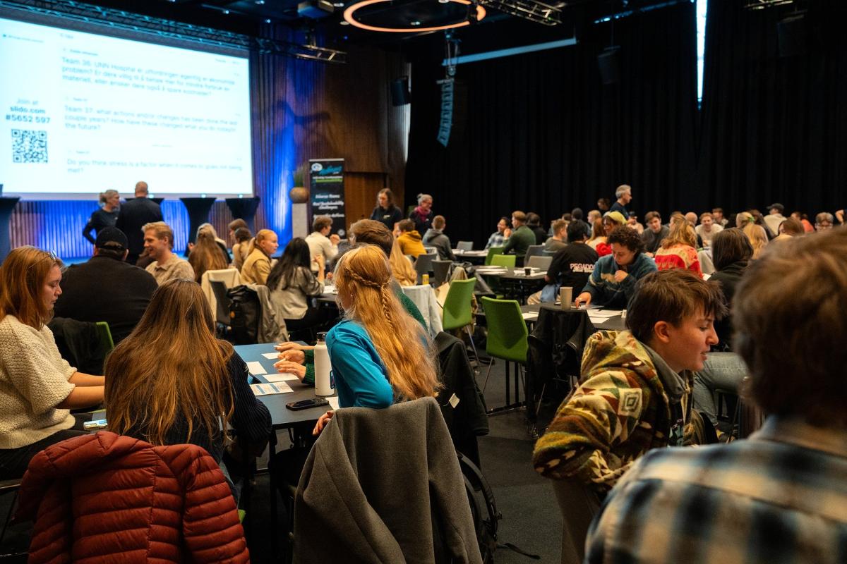 Engasjerte masterstudenter i konferansesal. 