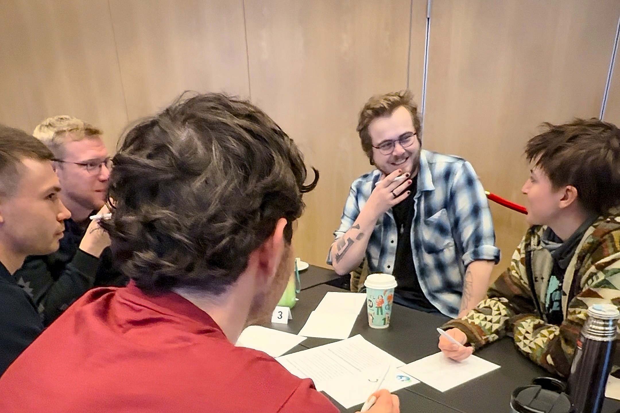 Studenter diskuterer rundt et bord i en konferansesal