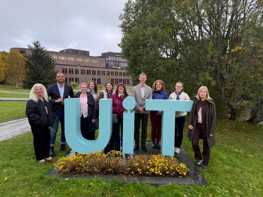 Stor gruppe mennesker foran UiTs logo på campus i Tromsø. Bente Haug, UiT, Carl Thodesen, OsloMet, Linn Dypdal, NMBU, Alexandra Ulrichsen, KD, Victoria Skogsletten Dalen, NSO, Ann Elin B. Andersen, UHR, Solve Sæbø, NMBU, Andrea Schneider, UiT, Ingrid Mikelsen, UD, Sigrunn Eliassen, UiB