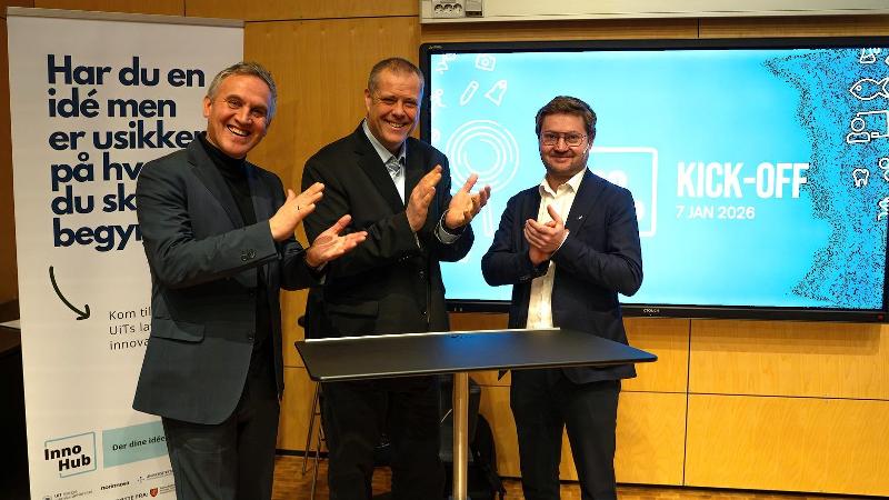 tre menn i dress smiler og klapper