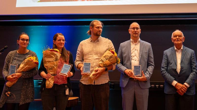 four researchers and an older man standing on a stage