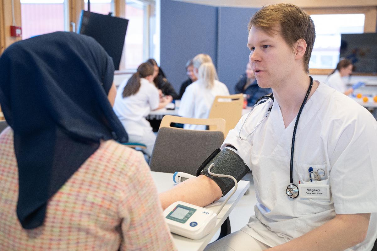 ein mann i helseklede snakkar med ei dame. dama har ryggen mot kamera.