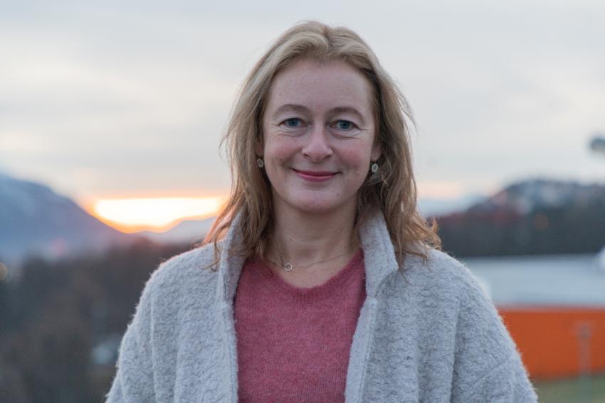 Kvinne smiler til kamera utendørs