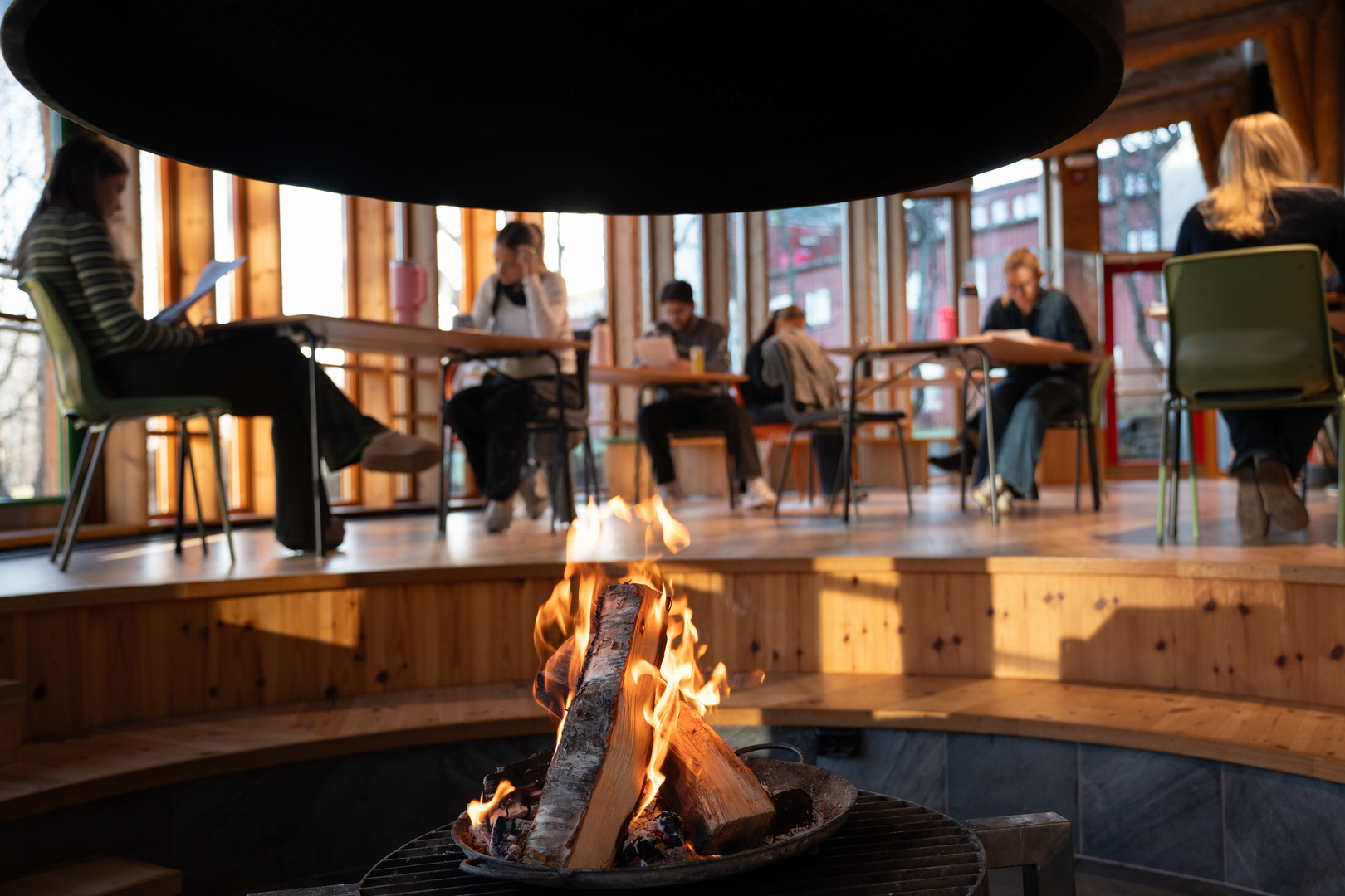 En gruppe studenter fordyper seg i pensum bak en b&aring;lplass inne p&aring; et samisk kulturhus. 